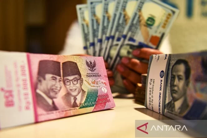 
 Petugas perbankan menunjukan uang pecahan rupiah dan dolar AS. (ANTARA FOTO/Muhammad Adimaja/Spt/aa.)