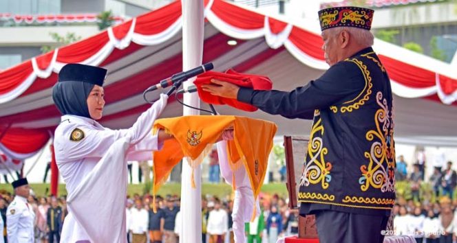 
 Dr. (H.C.) Ir. H. M. Basuki Hadimuljono, M.Sc., Ph.D., selaku inspektur upacara menyerahkan bendera Merah Putih kepada pembawa baki, Aulia Novita, siswi SMAN 2 Penajam Paser Utara, Kalimantan Timur. (Foto. Dok: Humas Otorita IKN)