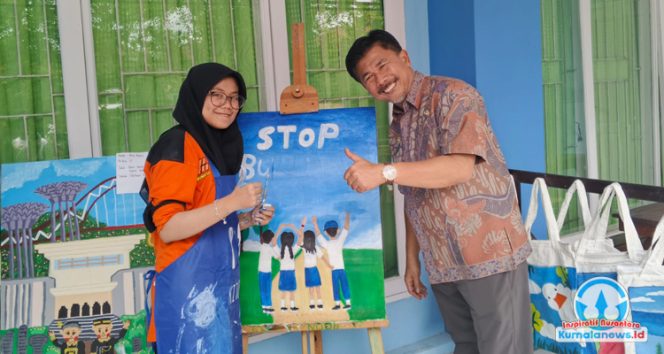 
 Sekretaris Daerah Kutai Kartanegara, Sunggono, berfoto bersama salah satu siswa SLB Negeri Tenggarong yang memamerkan hasil lukisannya.